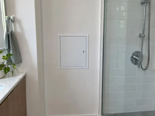 Small access panel in a painted bathroom wall beside a tiled shower in Bellevue Hill